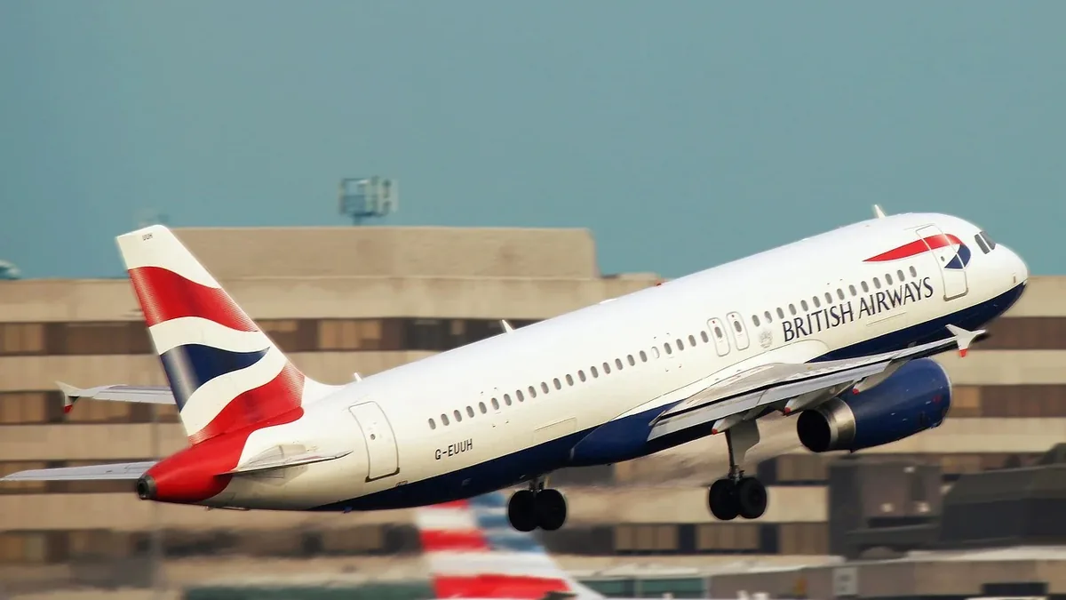 A British Airways airplane taking off from an airport, with the plane's white body and red, white, and blue tail visible.