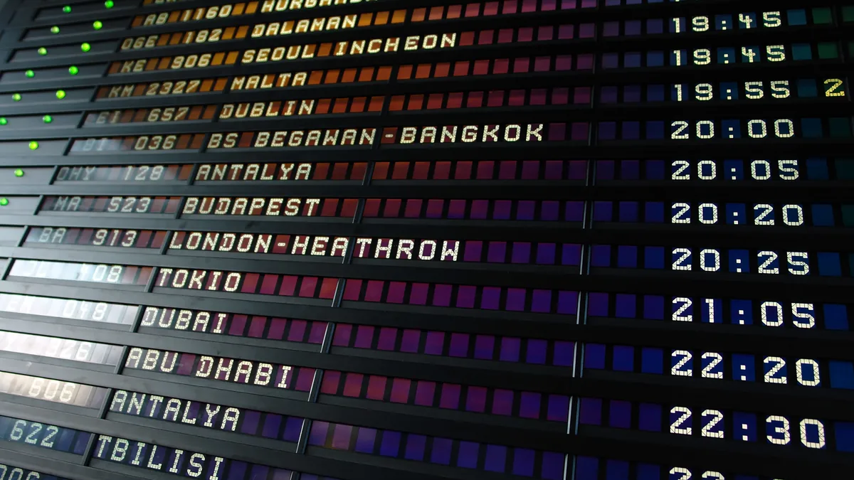 A large electronic departure board displaying flight information, including flight numbers, destinations, and departure times.